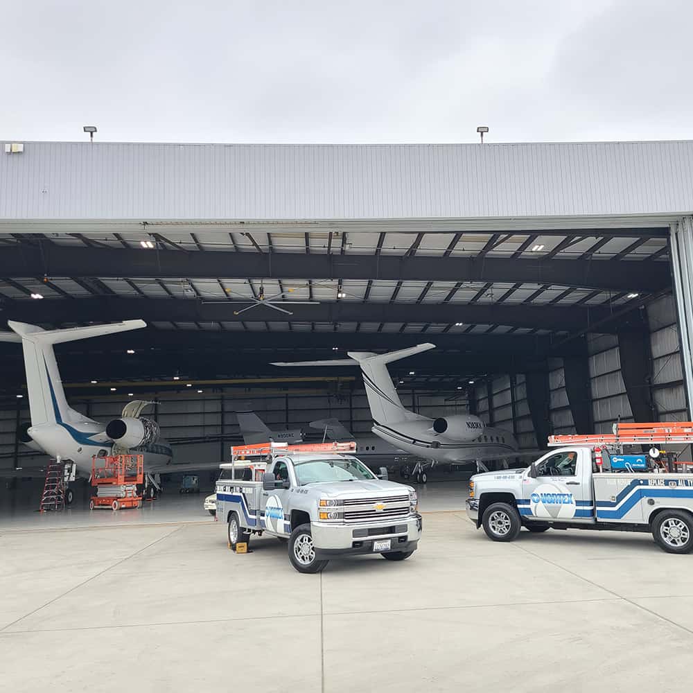 Vortex trucks parked in front of airplane hangar