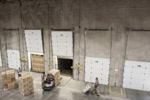 Uniformed workers loading boxed products into truck in a distribution warehouse.