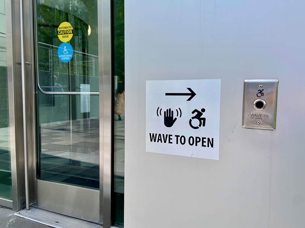Wave to open sign with a waving hand and wheelchair symbol