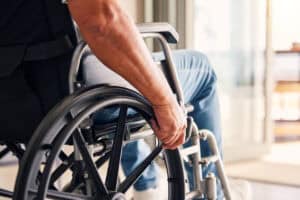 Man, hands and wheelchair for support, hope or travel in healthcare or medicare at home. Closeup of male or person with a disability moving on chair for mobility, surgery or wellness in the house.