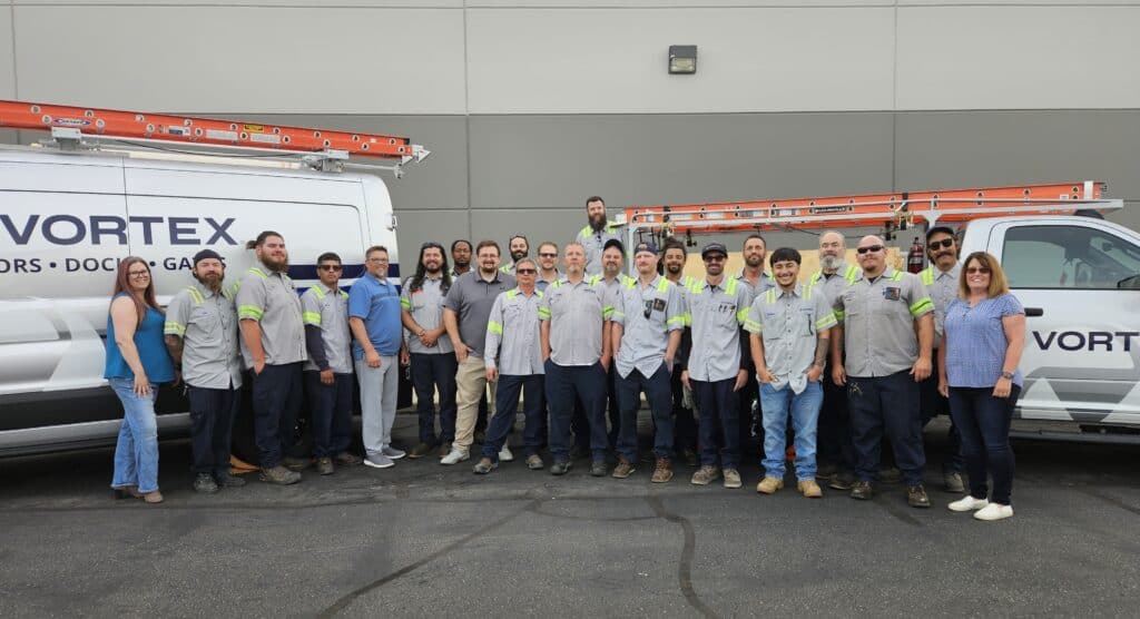 Vortex Doors Salt Lake City team standing in front of branded commercial door service vehicles.