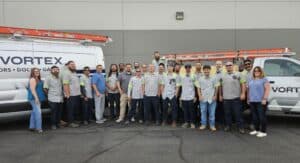 Vortex Doors Salt Lake City team standing in front of branded commercial door service vehicles.