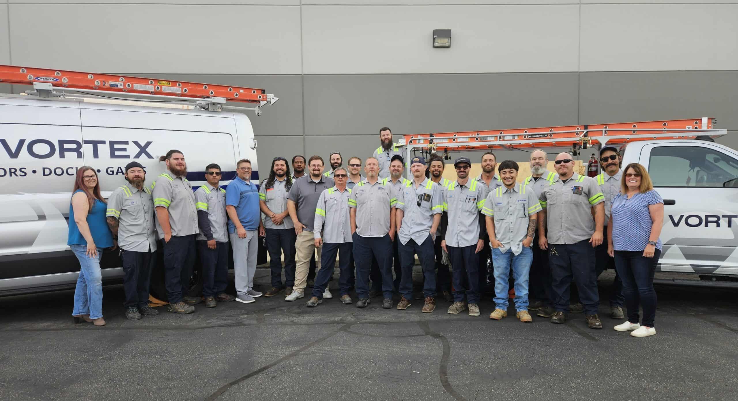 Vortex Doors Salt Lake City team standing in front of branded commercial door service vehicles.